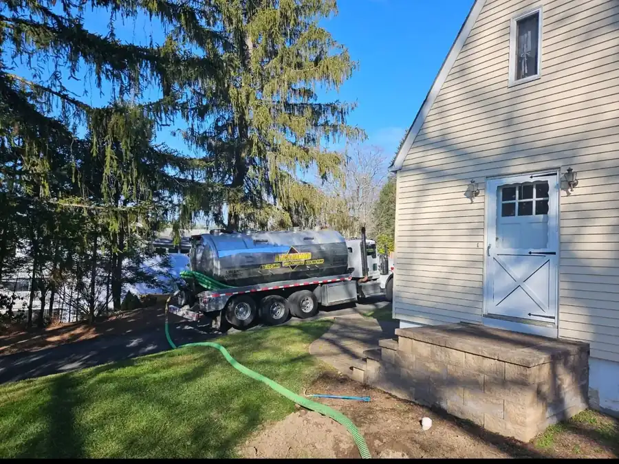 Black Diamond tanker beside a residential home with the suction hose run across the lawn to the tank